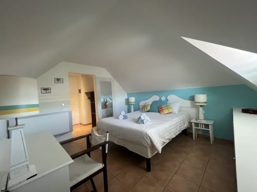 Chambre PREMIUM Tobago avec mur d'accent turquoise, lit queen-size, tête de lit blanche, tables de nuit et puits de lumière à Sainte-Anne