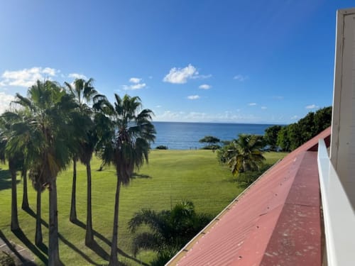 Balcon des Tropic Appartements avec vue sur les jardins tropicaux, la pelouse et la mer bleu à Sainte-Anne, Guadeloupe