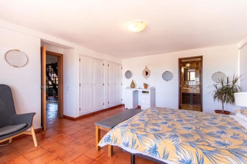 Quarto espaçoso na Villa Principezinho com azulejos em terracota, cama de casal, guarda-roupas brancos e vista para o mar
