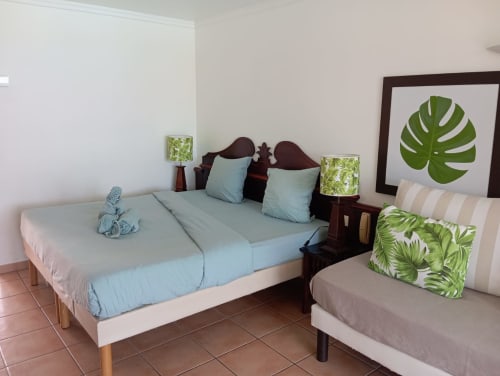 Chambre studio aux Tropic Appartements à Sainte-Anne avec lits jumeaux, décor tropical et accès balcon vue mer.