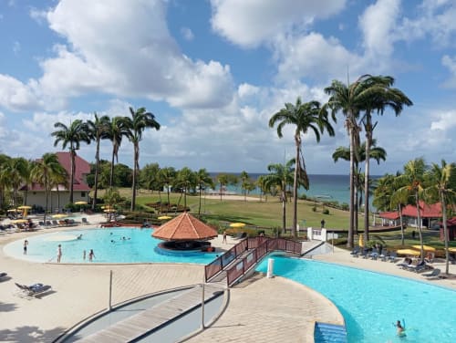 Complexe Tropic Appartements à Sainte-Anne avec piscines turquoise, palmiers, plage et vue sur mer