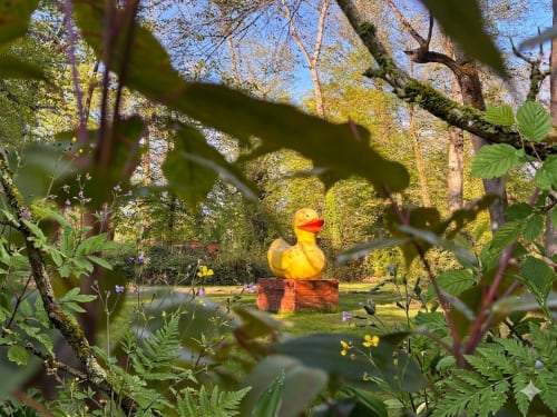 Giant yellow duck sculpture in lush garden at Les Lodges de Vaugrigneuse, Vaugrigneuse