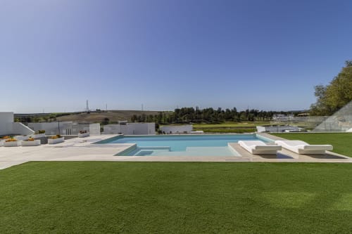Piscina infinita de lujo moderno con agua turquesa, tumbonas y jardín manicurado en G&H Apartments, Jerez de la Frontera