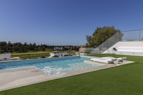 Lujosa piscina infinita en G&H Apartments de Jerez de la Frontera con tumbonas, jardín impecable y vistas al campo