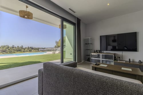 Apartamento de lujo moderno en G&H Apartments, Jerez, con piscina infinita, sofá gris, TV y vistas expansivas al lago