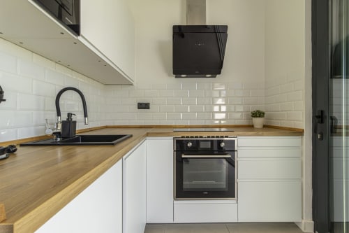 Cocina moderna en la casita de G&H Apartments en Jerez de la Frontera con muebles blancos, encimeras de madera y detalles negros
