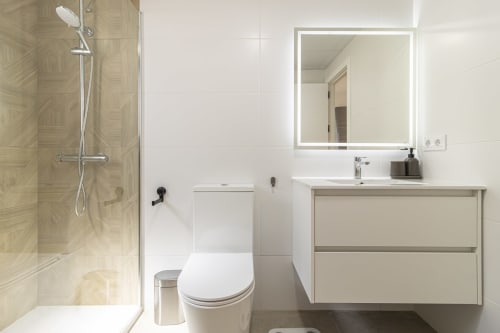 Baño moderno en Apartamentos G&H, Jerez de la Frontera, con ducha a ras de suelo, inodoro y tocador con espejo