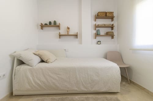 Dormitorio minimalista en G&H Apartments Jerez con cama, estantes de madera, cactus y mobiliario moderno
