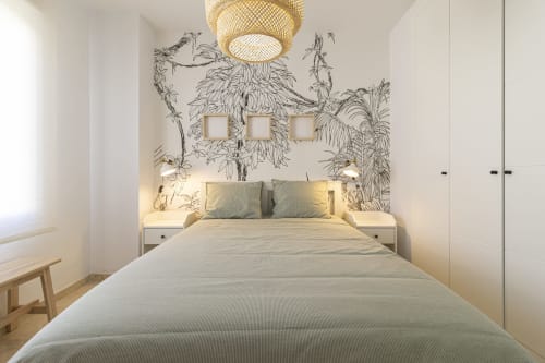 Dormitorio moderno en G&H Apartments Jerez con papel pintado botánico, lámpara de techo de ratán y ropa de cama neutra