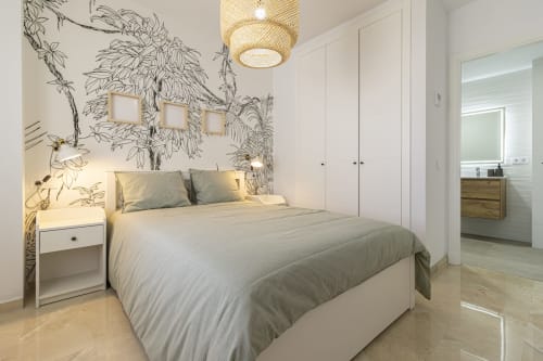 Dormitorio moderno en G&H Apartments de Jerez con papel tapiz botánico, cama queen, armario blanco y acceso a baño privado