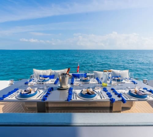 Élégante table côtière aux couverts bleu et blanc surplombant les eaux méditerranéennes à Centuri, Corse