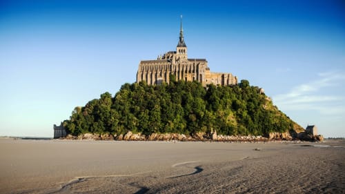 Mont Saint-Michel abbey on tidal island with sandy bay, Normandy France
