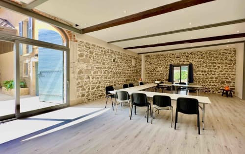 Salle de réunion moderne au Gîte La Chouette étoilée à Vaux-en-Beaujolais avec murs en pierre, poutres bois, portes vitrées et