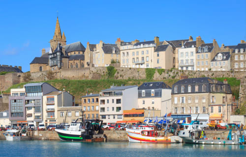 Colorful fishing boats and stone buildings in a French coastal harbor town