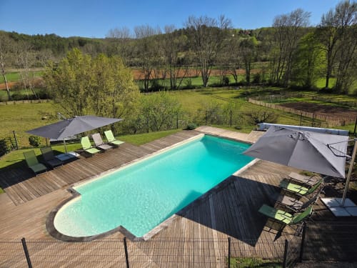 Piscine turquoise avec terrasse en bois, transats et parasols aux Gîtes Le Pech à Sainte-Foy-de-Longas