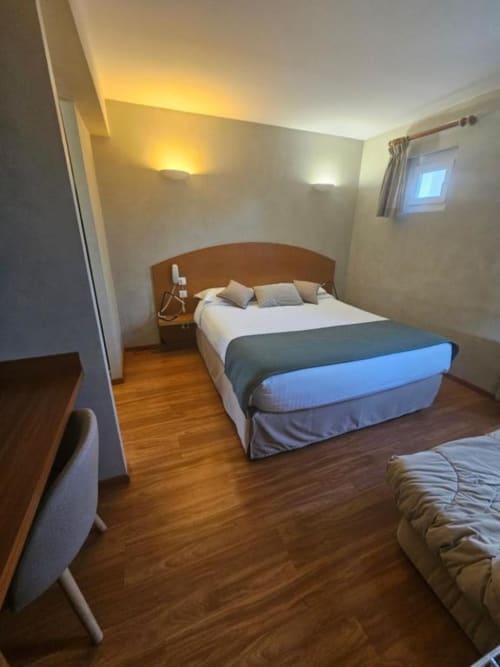 Chambre double confortable aux parquets en bois, lumière chaleureuse et mobilier moderne à l'Hôtel La Route d'Argent à Bozouls