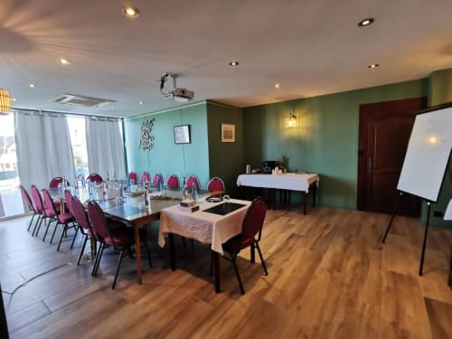 Salle de réunion moderne à La Route d'Argent avec chaises bordeaux, équipements de présentation et murs à accents verts