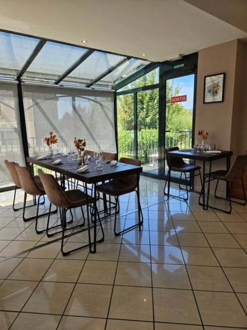 Salle à manger moderne de l'Hôtel La Route d'Argent avec toit vitrée, table noire, chaises marron et vues panoramiques sur Bozouls