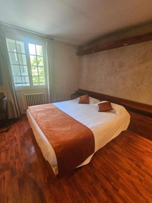 Chambre d'hôtel à La Route d'Argent à Bozouls avec lit queen-size, parquet et vue sur le jardin