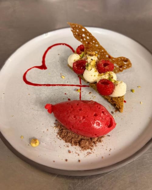 Dessert élégamment dressé au restaurant La Route d'Argent à Bozouls avec framboises, crème et tuile croustillante