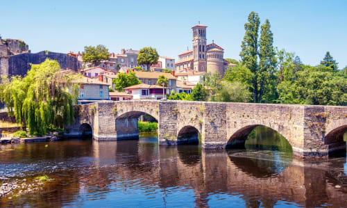 Pont de pierre historique enjambant la rivière avec bâtiments colorés et clocher d'église à Cholet, France