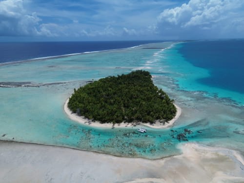 Vue aérienne de l'île de Tikehau avec son lagon turquoise cristallin, sa plage de sable blanc et sa végétation luxuriante à Tuherahera