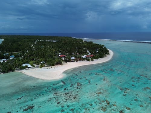 Vue aérienne du gîte Tikehau Herearii avec lagon turquoise, plage de sable blanc et palmiers à Tuherahera