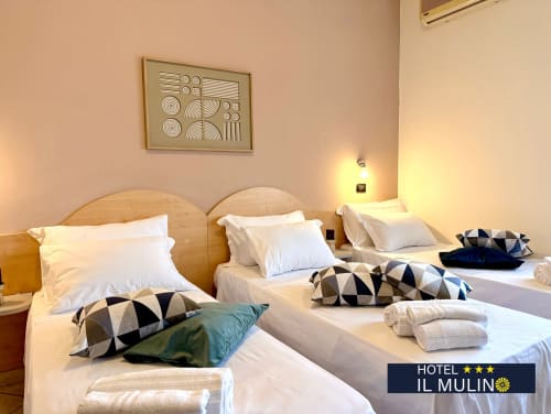 Camera matrimoniale all'Hotel Il Mulino di Villalunga con biancheria bianca, cuscini decorativi e arte moderna alle pareti