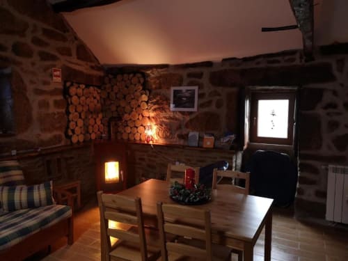 Interior rústico de villa em pedra com lareira, mesa de madeira, cadeiras e iluminação ambiente acolhedora em Casa da Avó Ana