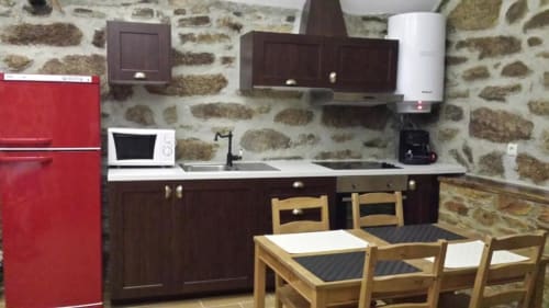 Cozinha rústica com geladeira vermelha, armários de madeira escura e cadeiras de madeira na vila Casa da Avó Ana, Mondim de Basto.