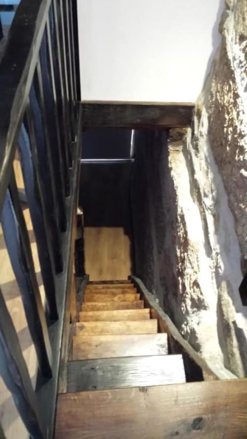 Escada de madeira descendo por corredor estreito de pedra na quinta Casa da Avó Ana, Mondim de Basto