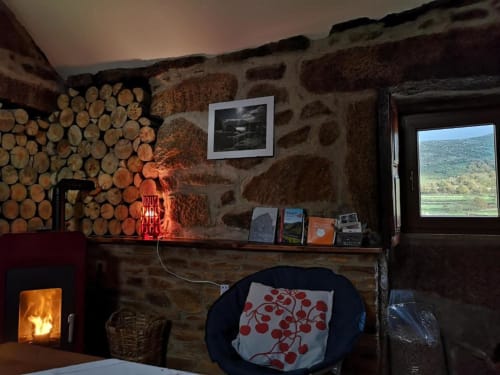 Interior aconchegante de villa de pedra com lareira, lenha empilhada, placa de neon vermelha, vista de montanha e decoração rústica em Casa da Avó