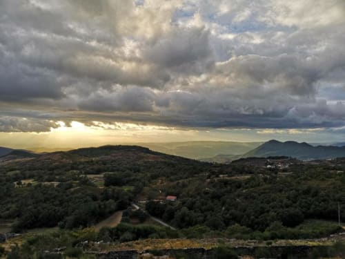 Vale montanhoso pitoresco na Casa da Avó Ana em Mondim de Basto, Portugal, com colinas florestadas e céu dramático nublado