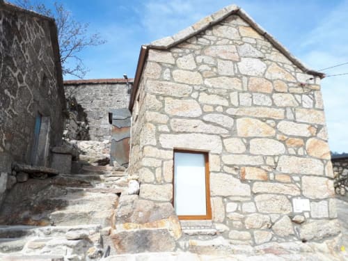 Exterior da casa de pedra da Casa da Avó Ana, Mondim de Basto Portugal com porta de madeira e vistas para a montanha