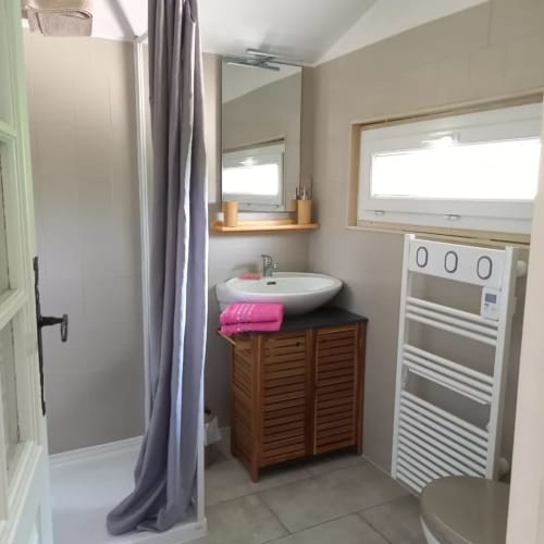 Salle de bain moderne du gîte Le Pech : vasque ronde, meuble en bois, douche, miroir et sèche-serviettes