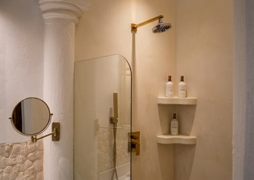 Baño de lujo en Villa Merida Boutique Hotel en Mérida con ducha de efecto lluvia, herrajes de latón y estantes de piedra