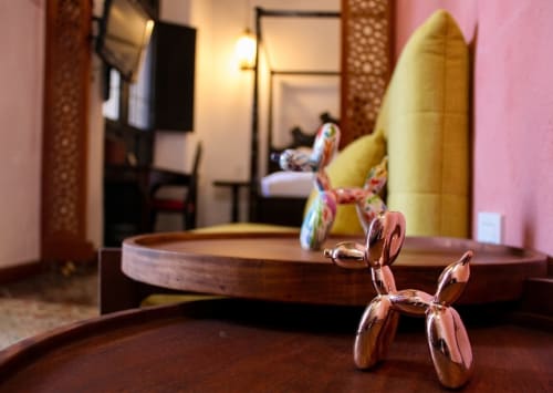 Esculturas de perros globo de colores y elementos decorativos en habitación del hotel boutique Villa Merida con paredes rosas y amarillas
