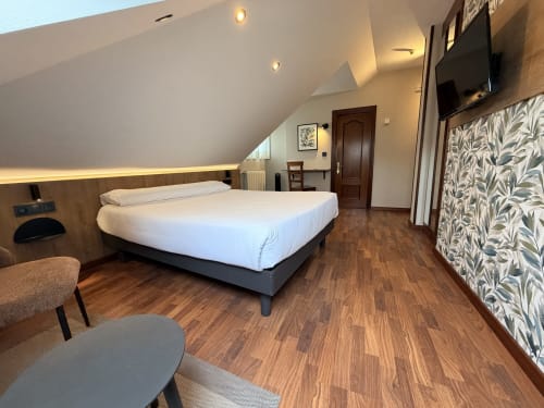 Habitación moderna del Hotel Puerto De Candás con cama queen, suelo de madera y vistas a la ciudad en Candás, Asturias