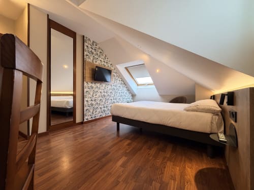 Moderno dormitorio abuhardillado en Hotel Puerto De Candás con cama doble, suelos de madera, claraboya y vistas de la ciudad de Candás, Asturias