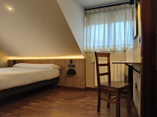 Moderno dormitorio de hotel con cama doble, mobiliario de madera y vistas a la ciudad en Hotel Puerto De Candás, Asturias