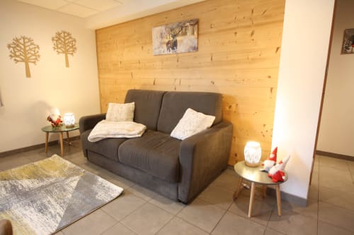 Salon douillet avec canapé sombre, mur en bois et décoration montagnarde au Domaine des Fleurs, Gérardmer.