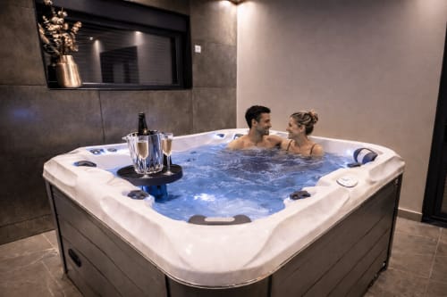Couple savourant le spa chaleureux de la suite de luxe SPA LE CLANDESTIN à Cambrai avec champagne et équipements spa modernes