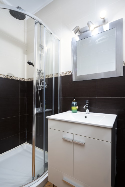 Banheiro moderno do apartamento PEDRO RB Algarve com azulejos preto e branco, pia branca, espelho e box de chuveiro