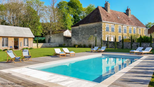 Piscine de luxe Casa Pertica avec transats, terrasse en bois et élégante maison jaune à Ceton, France