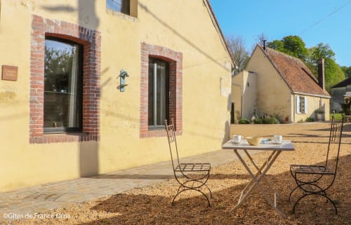 Cour de Casa Pertica avec cottage jaune, table de café et chaises en fer forgé à Ceton, France