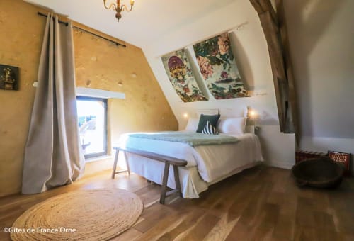Chambre douillette avec plafond mansardé, lit blanc, œuvres florales, parquet en bois à la Casa Pertica B&B à Ceton
