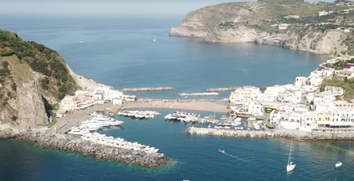 Vista aerea del Villa Bina Sea Hotel con edifici bianchi, marina con barche, scogliere spettacolari e acque turchesi a Serrara