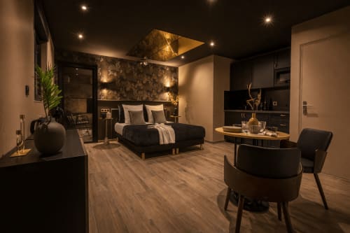 Suite spa luxueuse au Clandestin Arras avec lit noir, salon, parquet et éclairage ambiant
