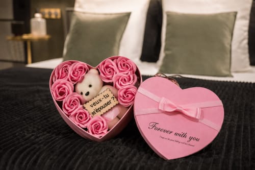 Boîte cadeau en forme de cœur avec roses roses et ours en peluche dans la Suite & Spa de l'hôtel Le Clandestin Arras
