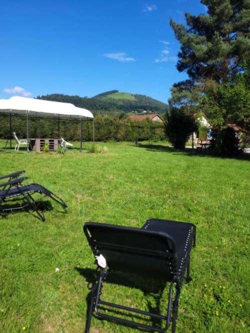 Jardin spacieux des Gîtes les Grandes voies avec transats, tente blanche et vue sur les montagnes